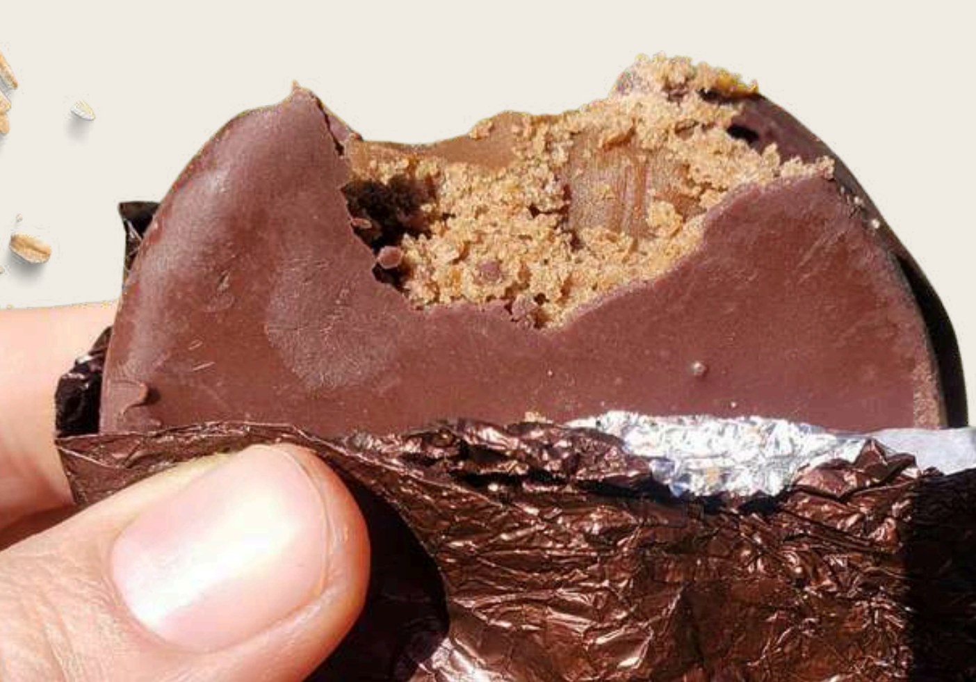 Alfajor de avena Madelina mordido, con cobertura de chocolate